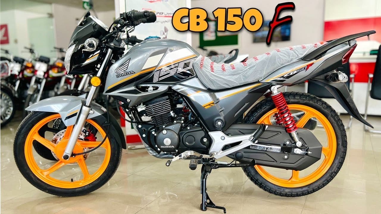 A sleek gray Honda cb 150 f motorcycle is displayed in a showroom. It features orange rims and red rear shocks, showcasing its sporty design. Perfect for exploring motorcycle accessories Pakistan at FancyBikes.pk.